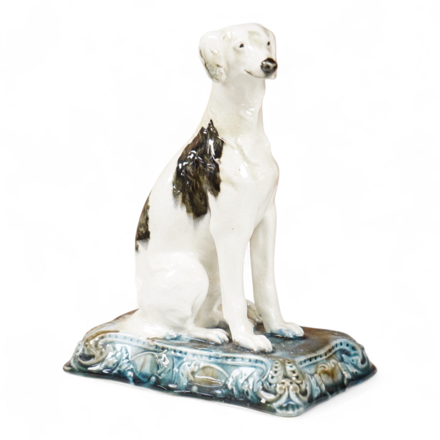 A Minton’s glazed pottery model of a seated Saluki, c.1905, stamped to the base, 15cm high